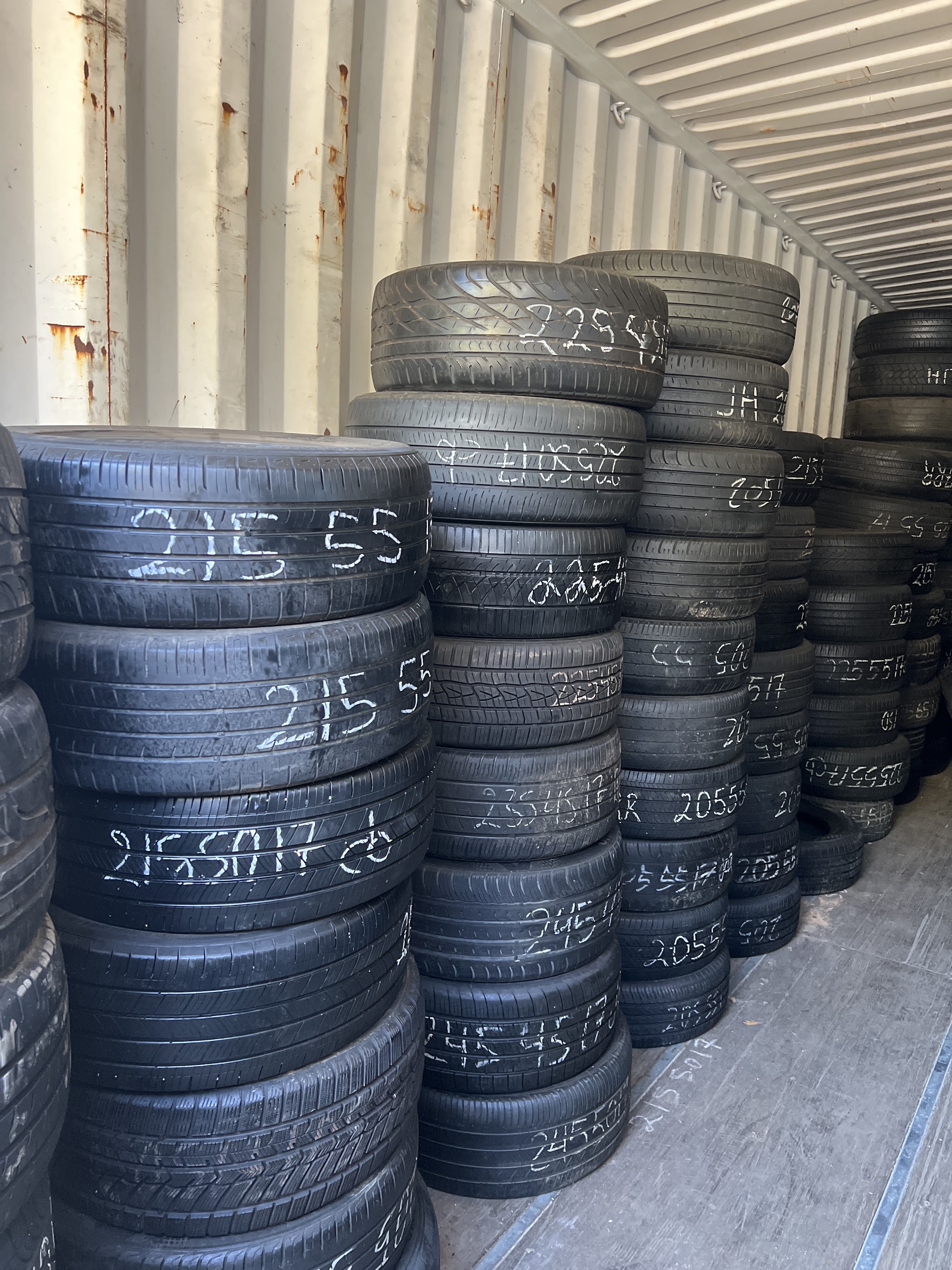 Stacks of used tires with sizes chalked on each one
