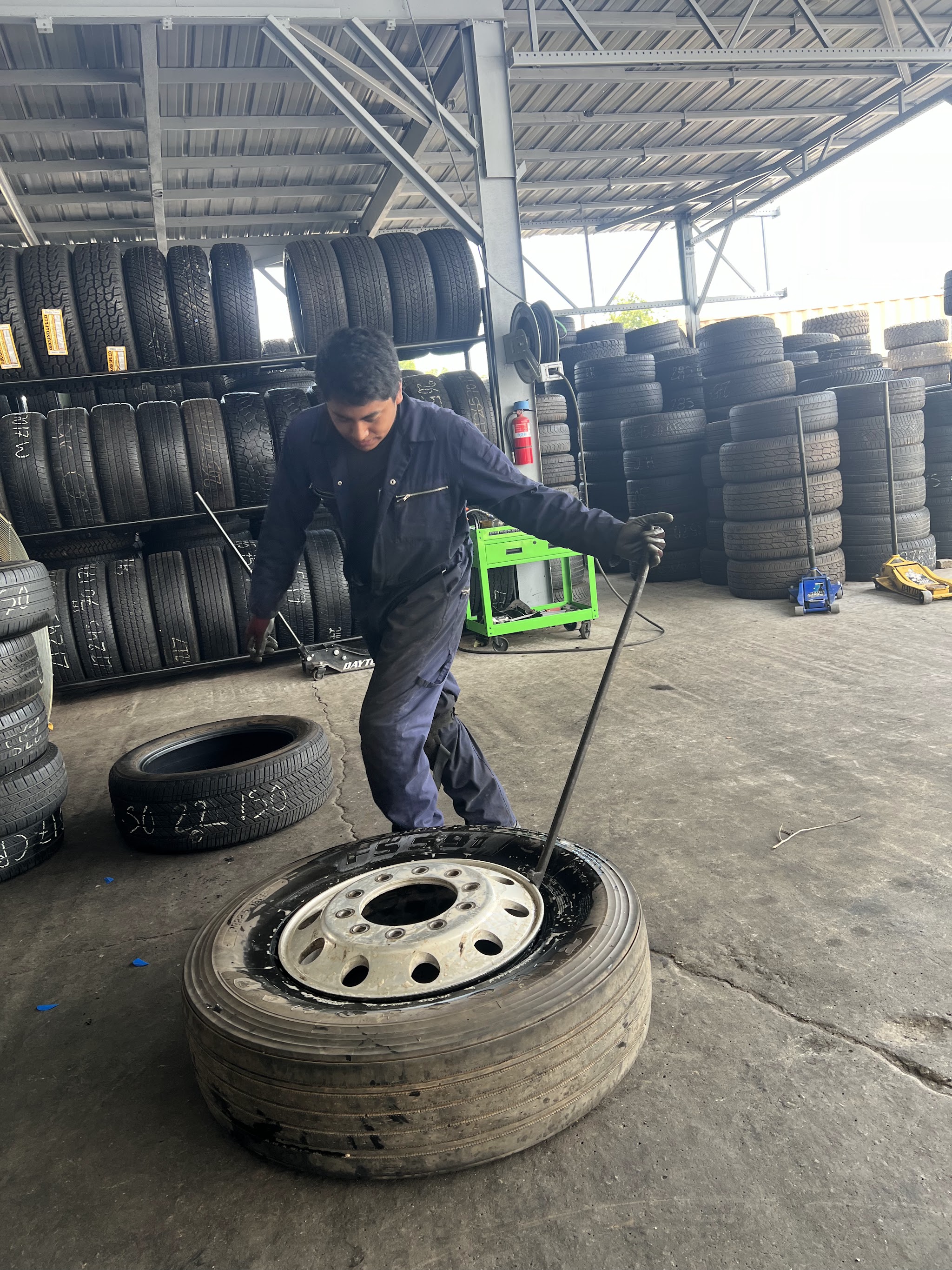 One of our team working a tire off its wheel with racks of tires behind